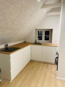 an attic kitchen with white cabinets and a window at Lejlighed i naturskønt område in Silkeborg