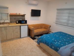 a bedroom with a bed and a kitchen with a sink at גבעת האלון in Ein Kinya