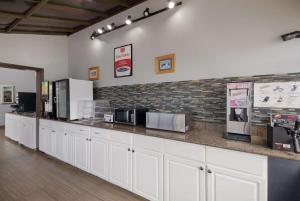 a kitchen with white cabinets and a brick wall at Econo Lodge near The Domain - The Arboretum in Austin