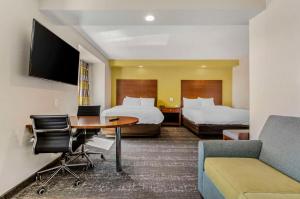 スタントンにあるClarion Pointe Staunton Eastのベッド2台、テーブル、ソファが備わるホテルルームです。
