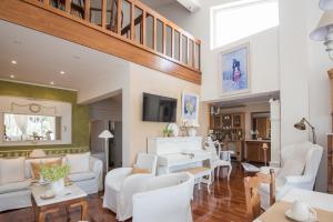 a living room with white furniture and a staircase at Unique house by the sea in Paralía Proastíou