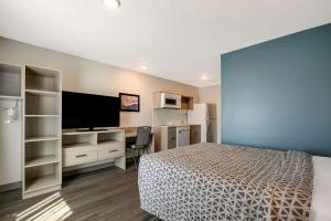 a bedroom with a bed and a desk and a television at WoodSpring Suites Knoxville - Cedar Bluff in Knoxville