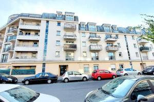 un gran edificio con coches estacionados frente a él en Cosy Home 2, Cergy Le Haut, 6 personnes, 3 min gare, 30 min Paris, parking privé en Cergy