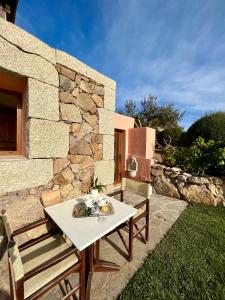 a table and a bench next to a stone wall at Villa Kalypso - Porto Cervo in Porto Cervo