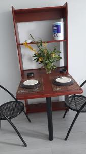 a table with two plates and a vase of flowers on it at STUDIO TRES PROPRE de 18 m2 in Cergy