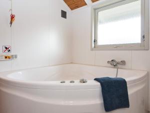 a white bath tub in a bathroom with a blue towel at 8 person holiday home in Juelsminde in Sønderby