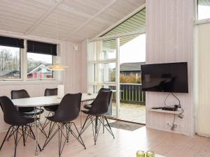 a dining room with a table and chairs and a television at Three-Bedroom Holiday home in Juelsminde 18 in Sønderby