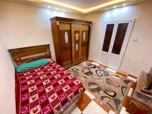 ein Schlafzimmer mit einem Bett, einer Kommode und einer Tür in der Unterkunft The Home in Al-Fayyūm