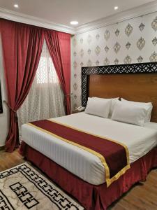 1 dormitorio con 1 cama grande y cortinas rojas en فندق ساسو سويت للوحدات المفروشه والفندقيه en Farasan