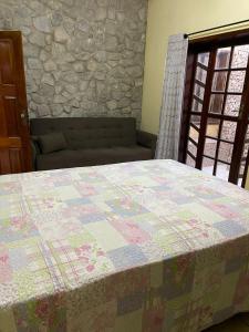 a bed in a room with a stone wall at Casa Sol nascente in Triunfo