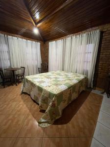 a bedroom with a bed with a table and windows at Casa Sol nascente in Triunfo
