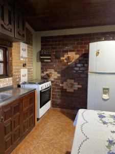 a kitchen with a white refrigerator and a brick wall at Casa amanhecer in Triunfo