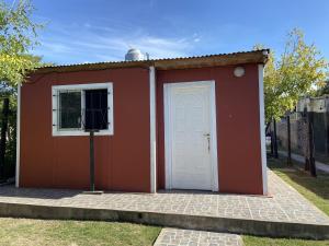 um pequeno barracão vermelho com uma porta branca em Casa estilo Americana Bruno - a 15 min del Aeropuerto em Barrio Esteban Echeverría