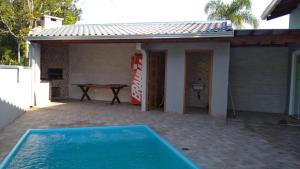 a swimming pool in front of a house with a table at Casa com piscina - Itapoá in Itapoa