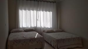 a bedroom with two beds in front of a window at Casa com piscina - Itapoá in Itapoa