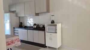 a kitchen with a white refrigerator and a microwave at Casa com piscina - Itapoá in Itapoa