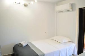 a bedroom with a white bed with a gray ottoman at Calma Kourouta Apartments in Kourouta