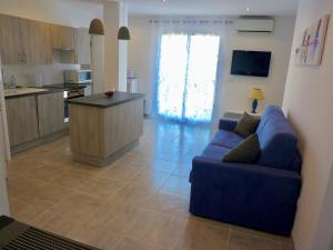 a living room with a blue couch and a kitchen at Les bougainvilliers in Penta-di-Casinca +29 photos