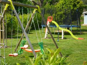 un parque infantil con columpios coloridos en un parque en Les bougainvilliers, en Penta-di-Casinca
