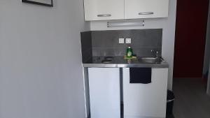 une petite cuisine avec un évier et une bouteille. dans l'établissement STUDIO TRES PROPRE de 18 m2, à Cergy