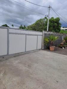 a white fence with plants in front of it at Laure hebergement loue des lits en dortoir in Faaa