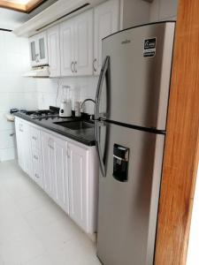 einen Kühlschrank aus Edelstahl in einer Küche mit weißen Schränken in der Unterkunft Excelente ubicación y acogedor apartamento in Manizales