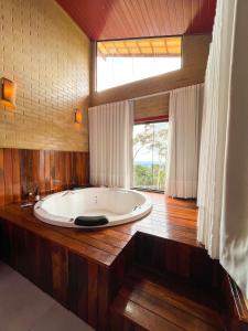 uma grande banheira num quarto com uma janela em Chales Labelle - 5 minutos do Centro e da Rodoviária de Santa Teresa em Santa Teresa