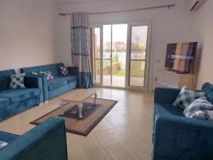 uma sala de estar com dois sofás azuis e uma mesa em Chalet Rosana Resort الساحل الشمالى em Dawwār al Ḩajj Aḩmad