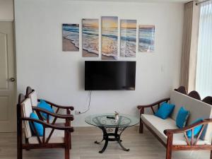 a living room with two chairs and a tv at Casa de playa con piscina en estreno in Camaná