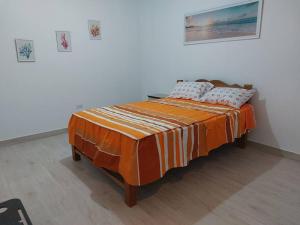 a bed with an orange comforter in a room at Casa de playa con piscina en estreno in Camaná