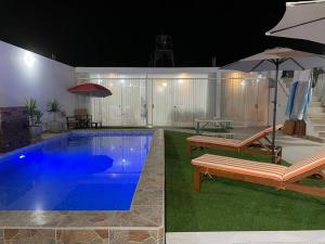 a swimming pool with a bench and an umbrella at Casa de playa con piscina en estreno in Camaná