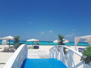 einen Holzsteg zum Strand mit Sonnenschirmen in der Unterkunft Chalet Rosana Resort الساحل الشمالى in Dawwār al Ḩajj Aḩmad