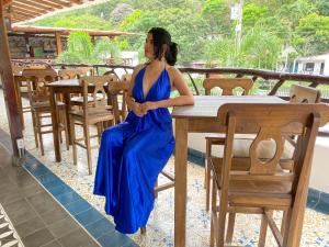 Una mujer con un vestido azul sentada en una mesa en Tayrona Suites en El Zaino