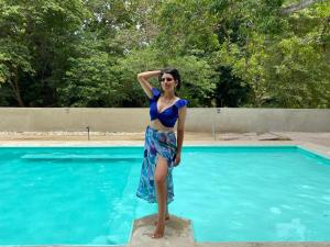een vrouw in een blauwe jurk die naast een zwembad staat bij Tayrona Suites in El Zaino