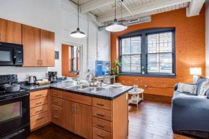 a kitchen with a sink and a couch in a room at NY Style Centric Loft w/ KingBed in Rochester