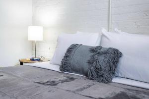 een bed met witte kussens en een grijze deken erop bij NY Style Centric Loft w/ KingBed in Rochester