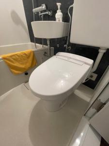 a white toilet in a bathroom with a yellow towel at Kawasaki Station Inn in Kawasaki