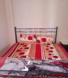 a bed with a red comforter and pillows on it at Khalid in Beni Mellal