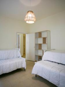 a room with two beds and a light fixture at La Casa de la Plaza in San Antonio de Areco