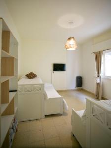 a white room with two beds and a tv at La Casa de la Plaza in San Antonio de Areco +9 photos