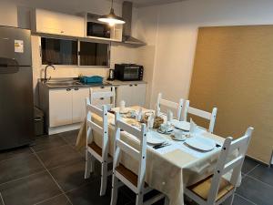a kitchen with a table with white chairs and a kitchen with a refrigerator at Apart del Este 5 in Paysandú