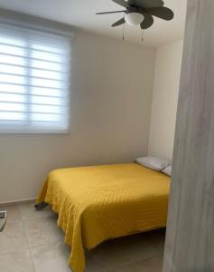 a bedroom with a yellow bed with a ceiling fan at Confortable depto con alberca in Zapopan