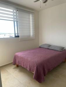 a bedroom with a purple bed and a window at Confortable depto con alberca in Zapopan