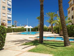 une piscine avec des palmiers à côté d'un immeuble dans l'établissement Ventana al Mediterráneo, à Jávea