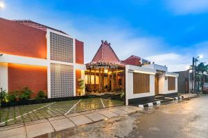 a home with a building with a pond in front of it at KESATRIYAN JOGJA GUEST HOUSE in Yogyakarta