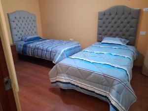 two beds in a bedroom with blue comforter at Bonito departamento - Cayma in Arequipa