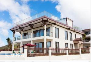 ein weißes Gebäude mit einem Balkon und einem Pool in der Unterkunft Hanamitsu Hotel & Spa in Garapan