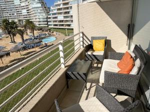balcón con sillas, mesa y piscina en Precioso San Alfonso del Mar, en Algarrobo