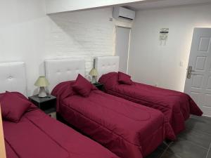 três camas com lençóis vermelhos num quarto em Apart del Este Loft 6 em Paysandú