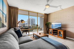 a living room with a couch and a tv at Surf Dance Apartments in Coolum Beach